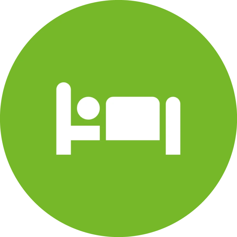 Weißes Piktogramm einer liegenden Person im Bett auf grünem Kreis – symbolisiert Gästewohnung